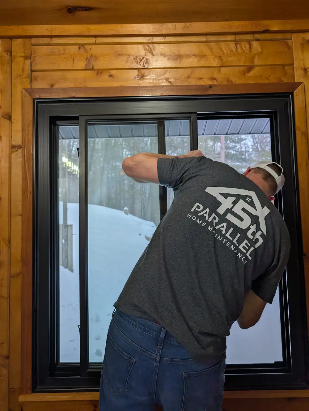 Licensed builder adjusting window frame during handyman service call in Traverse City, Michigan